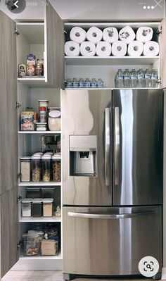 a stainless steel refrigerator in a kitchen next to shelves with rolls of toilet paper on them