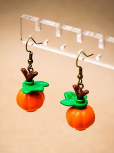 a pair of oranges with green leaves hanging from hooks on a hook - up display