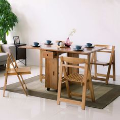 a wooden table with chairs around it in front of a couch and potted plant