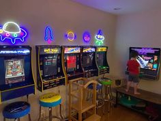 two children playing video games in a room with neon lights on the walls and stools