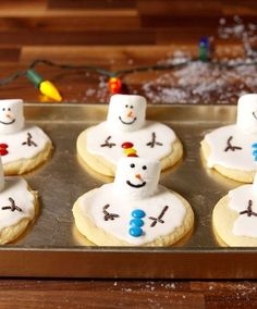 frosted sugar cookies decorated like snowmen on a baking sheet