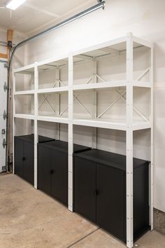 an empty room with white shelves and black bins