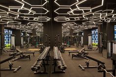 an empty gym with rows of exercise machines and lights hanging from the ceiling above them