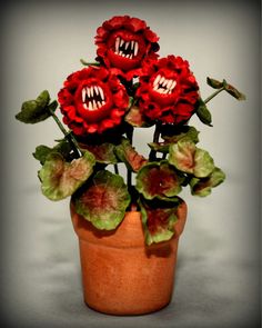 three red flowers with mouths on them in a pot