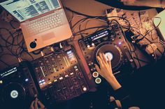 a person using a laptop computer on top of a dj's equipment set up