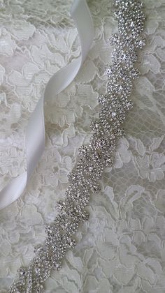 "Sparkling silver bridal sash adorned with rhinestones. Securely fastened onto a quality double faced satin ribbon which ties into a bow and drapes down the back of your wedding dress. Perfect finishing touch for your wedding attire! Please make your choice of rhinestone trim length, ribbon colour, no ribbon or hook and eye closure from the drop down menus. Contact me if you have a custom length requirement. Ribbon options to purchase: You may purchase just the rhinestone trim ( no ribbon ) The Silver Sashes For Bridal Party Accessories, Silver Crystal Sashes With Rhinestones, Silver Bridal Accessories With Sashes For Party, Silver Bridal Accessories For Party, Silver Crystal Bridal Belt For Wedding, White Crystal Wedding Sash, Wedding Sash Belt, Wedding Sash, Bridal Sash