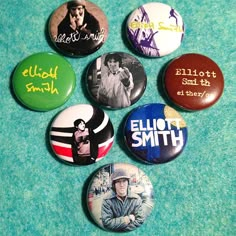 six button badges are arranged on a green surface