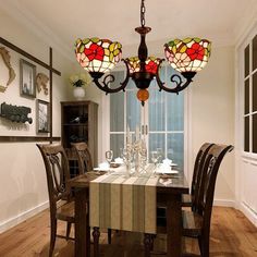 a chandelier hanging from the ceiling over a dining room table with four chairs