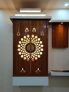 an intricate wooden door with bells on the front and side, in a room with white walls