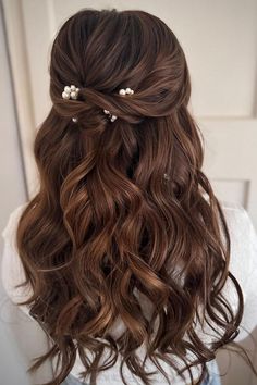 the back of a woman's head with wavy hair and flowers in her hair