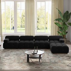 a living room with black couches and large windows in the back ground, along with a rug on the floor