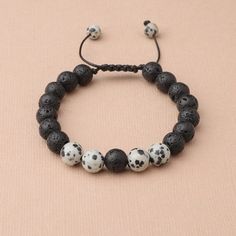 This handmade wax cord bracelet features Dalmatian Jasper and lava stones. Dalmation Jasper is a stone of action, calming the overactive mind while also promoting motivation and enthusiasm. It is known to encourage a child-like joy and energy, as well as reflection and self-examination. Lava Beads are made from Natural Volcanic Basalt. The lava stones acts as a sponge-like carrier as it soaks up your oils and retains them in the core of the Bead. Casual Braided Bracelets With 8mm Beads As Gift, Casual Braided Bracelets With 8mm Beads For Gifts, Casual Lava Stone Bracelet With Natural Stones, Casual Adjustable Bracelets For Meditation, Casual Everyday Lava Stone Beaded Bracelets, Casual Lava Stone Beaded Bracelets For Everyday, Casual Braided Bracelets With Natural Stones For Healing, Casual Adjustable Lava Stone Beaded Bracelets, Casual Adjustable Lava Stone Jewelry