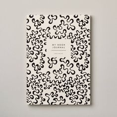 a book with black and white designs on the cover is sitting on a gray surface