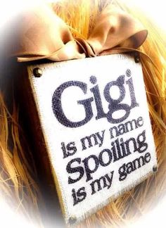 a close up of a sign with a bow on it's head and the words gigi is my name spoiling is my game