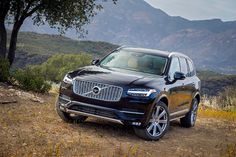 a black volvo suv parked on a dirt road