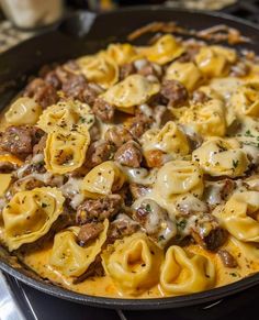 a skillet filled with pasta and meat covered in cheese