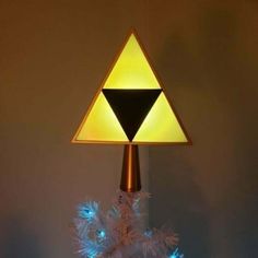 a triangle shaped lamp on top of a white christmas tree with blue lights around it