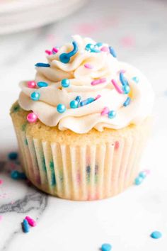 a cupcake with white frosting and sprinkles