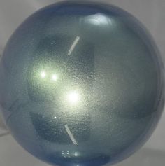 a blue glass ball sitting on top of a white tableclothed surface with the reflection of an object in it