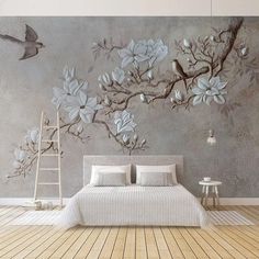 a bed sitting under a painting on top of a wall next to a wooden floor