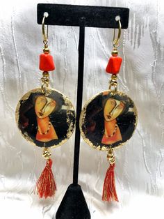 Handmade earrings, length 13 cm excluding the hook Nickel free hook Image of a painting by Modigliani printed on a wooden base finished with gold leaf, coral paste, tassels and golden elements complete the earrings Red Hand Painted Drop Earrings, Bohemian Orange Drop Chandelier Earrings, Bohemian Orange Drop Earrings, Artistic Orange Drop Earrings, Vibrant Orange Drop Earrings, Wooden Base, Handmade Earrings, Gold Leaf, Tassels