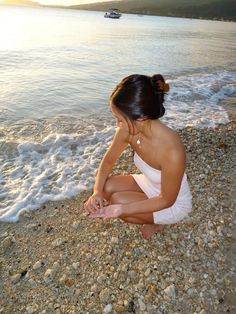 a woman sitting on top of a beach next to the ocean