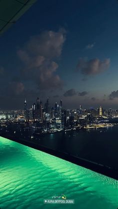 an outdoor swimming pool with city lights in the background