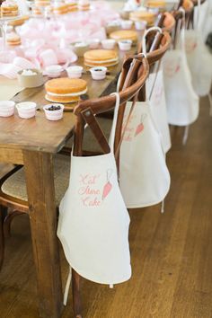 a table filled with lots of cupcakes on top of wooden chairs