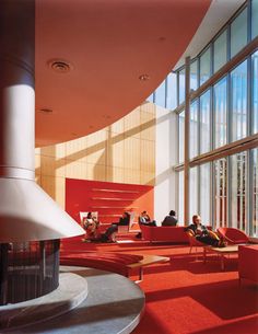 people sitting on red couches in a large room with tall windows and floor to ceiling windows