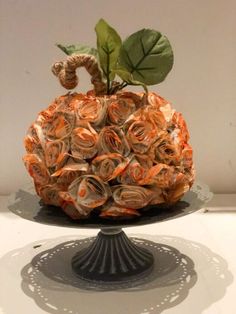 an orange and white decorative object sitting on top of a cake plate with a green leaf