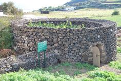 there is a stone building made out of rocks and grass in the yard with a green sign on it