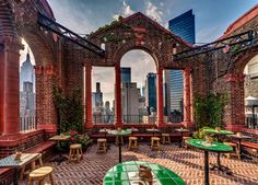 an outdoor dining area with tables and benches in the middle of it, surrounded by tall buildings