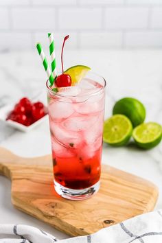 a red drink in a glass with a green and white striped straw garnish