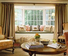 a living room filled with furniture and a large window covered in windowsills next to a coffee table