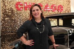 a woman standing in front of an old car