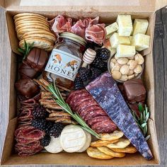 a box filled with different types of meats, cheese and crackers on top of a wooden table