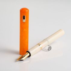 an orange fountain pen sitting on top of a white table