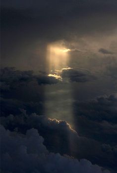 the sky is filled with dark clouds and light shining from behind an object in the distance