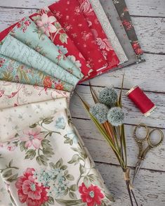 a bunch of fabric and scissors sitting on a table next to each other with flowers in them