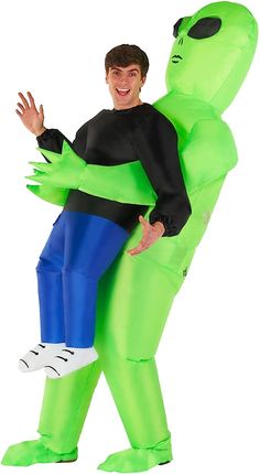 a man in an inflatable costume is carrying a giant green alien like creature