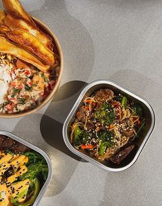 three containers filled with food sitting on top of a gray counter next to each other