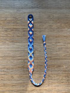 a blue and white lanyard with a knot around it on a wooden table next to a cell phone