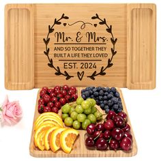 a wooden cutting board with fruit on it and a couple's wedding date engraved on the back