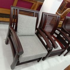 three wooden chairs sitting next to each other on a white floor in a room with purple walls