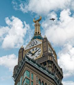 a large clock tower with a bird flying in the sky above it and clouds behind it