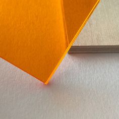 an orange piece of paper sitting on top of a white surface