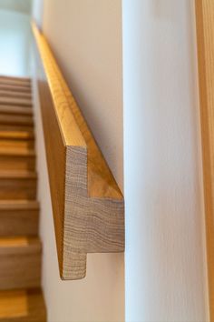 a close up of a wooden shelf on the side of a wall next to a stair case