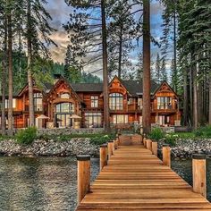 a wooden dock sitting next to a large house on top of a body of water