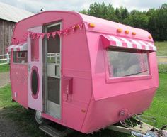 a pink trailer parked on top of a grass covered field