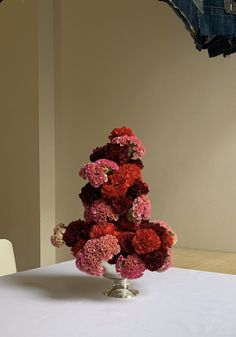 a table topped with a tall metal vase filled with red and pink carnations